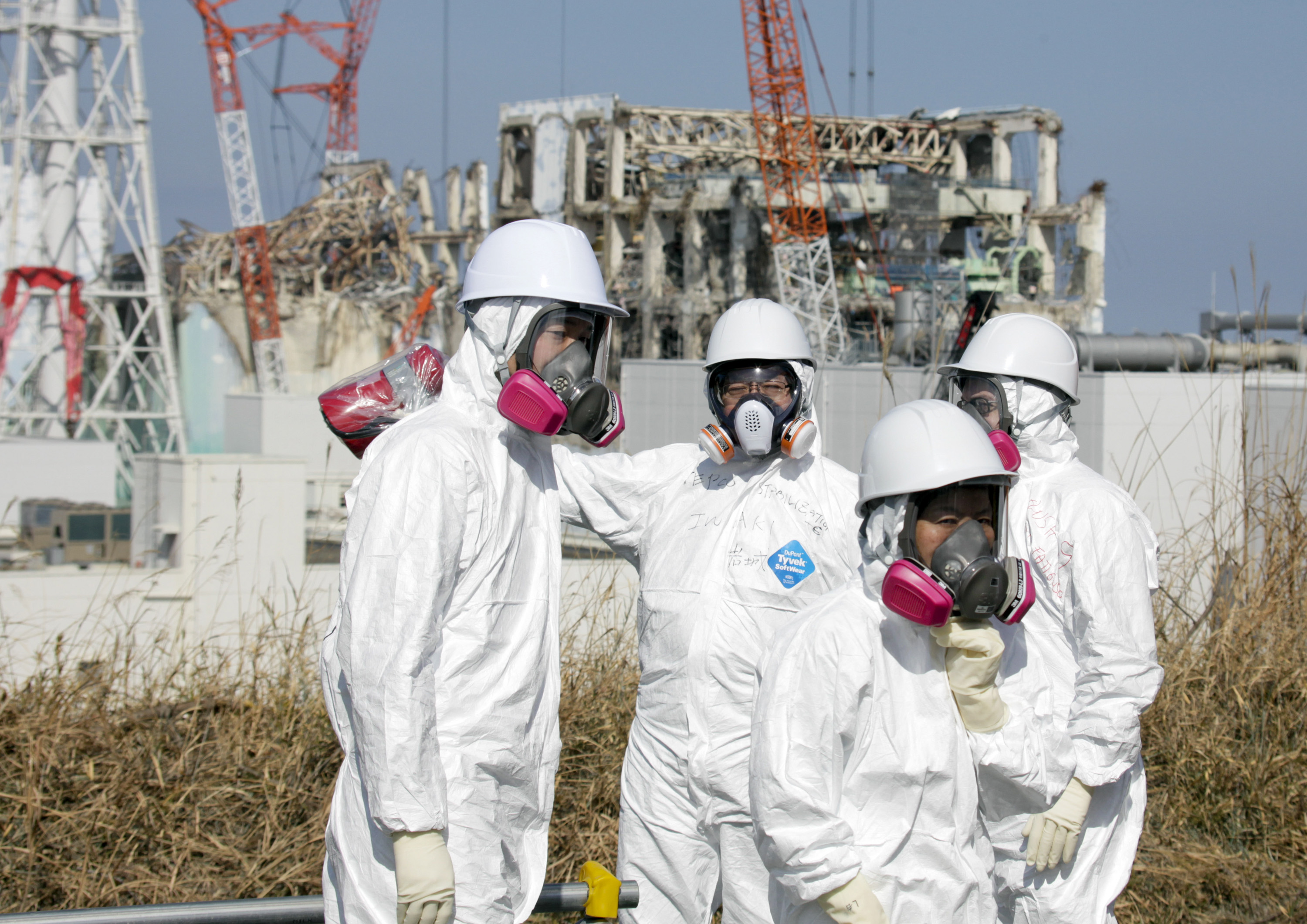 Member of the media, escorted by TEPCO employees, wearing protective suits and masks, look at the Unit 3 and Unit 4 reactor buildings of Tokyo Electric Power Co. (TEPCO)'s tsunami-crippled Fukushima Daiichi nuclear power station in Okuma, Fukushima prefecture, northeastern Japan, Tuesday, Feb. 28, 2012. (AP Photo/Kimimasa Mayama, Pool)